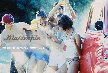 Group of Teenagers Having Water Fight while Washing Truck