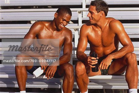Hommes assis sur les gradins au repos après une séance d'entraînement en plein air