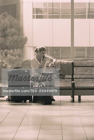 Businesswoman Sitting on Bench Using Cell Phone in Terminal