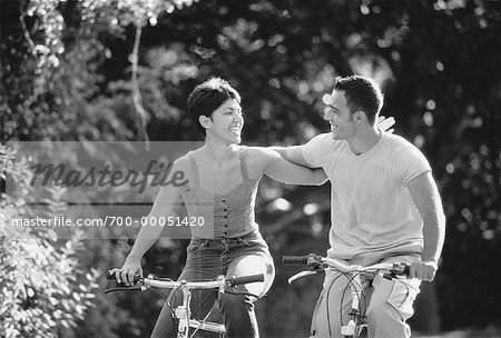Couple Riding Bicycles Arm in Arm In Park