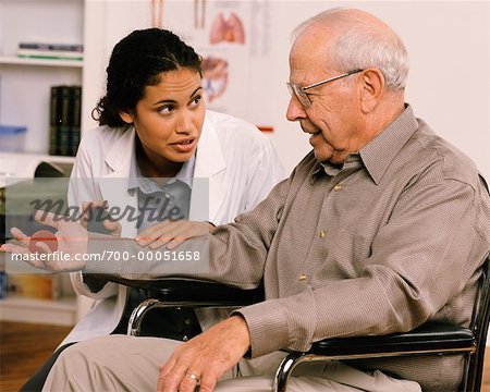 Female Physiotherapist Talking to Mature Male Patient in Wheelchair