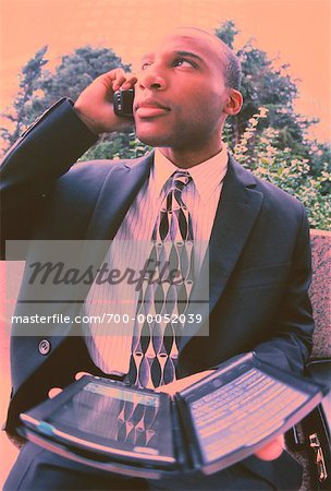 Businessman Using Electronic Organizer and Cell Phone Outdoors