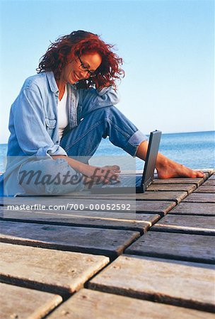 Femme assise sur le quai à l'aide d'ordinateur portable