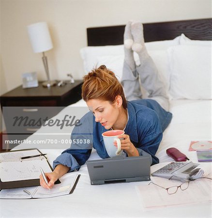 Femme allongée sur le lit avec Mug, Agenda et ordinateur portable