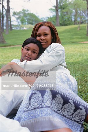 Portrait of Mother and Daughter Sitting on Grass Embracing