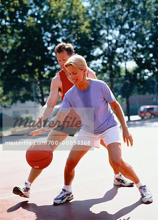Mature Couple Playing Basketball In Park