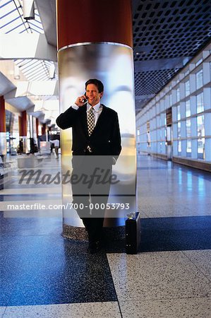 Homme d'affaires, se penchant sur la borne à l'aide du téléphone cellulaire dans le Terminal