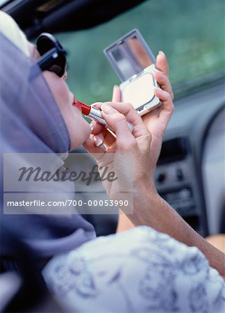 Mature femme assise dans la voiture, appliquer le rouge à lèvres