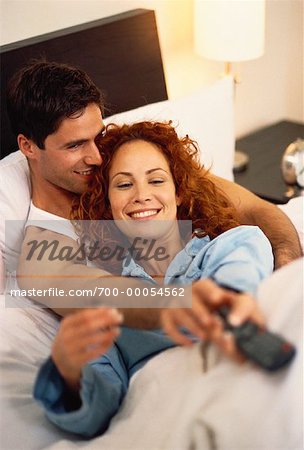 Couple au lit, disputent à télécommande de télévision