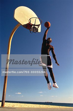 Man Jumping to Slam Dunk Basketball