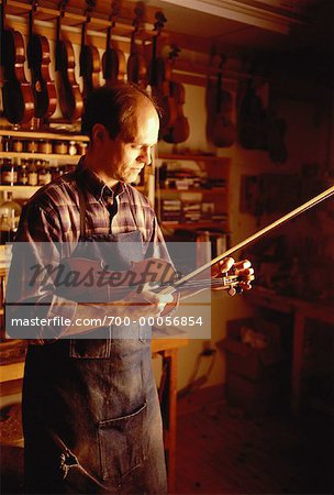Luthier Holding Violin in Workshop