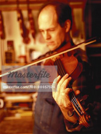 Luthier Playing Violin in Workshop