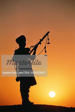 Silhouette of Man with Musical Instrument at Sunset Rajsalmer, India