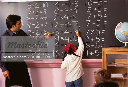 Männliche Lehrer gerade Mädchen schreiben an die Tafel im Klassenzimmer