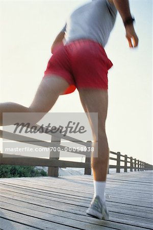 Back View of Man Running on Boardwalk