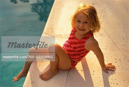 Portrait de jeune fille en maillot de bain assis près de la piscine