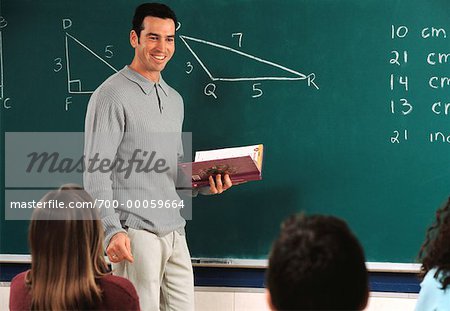 Male Teacher Standing near Blackboard, Holding Book