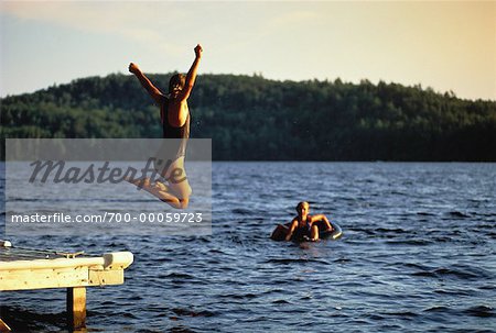 Girl in Swimwear, Jumping off Dock into Water Belgrade Lakes, Maine, USA