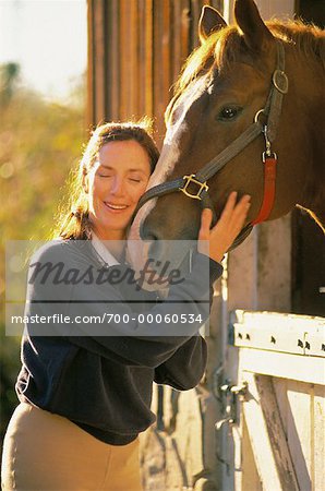 Mature femme embrassant avec cheval à l'écurie