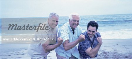 Portrait of Grandfather, Father And Son Flexing Muscles on Beach