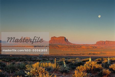 Übersicht über Felsformationen und Landschaft bei Sonnenaufgang mit Vollmond, Monument Valley, UT, USA