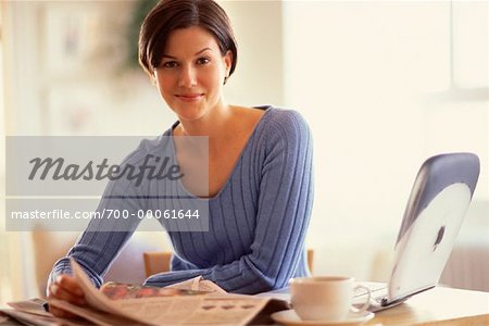 Porträt der jungen Frau an Tisch mit Zeitung