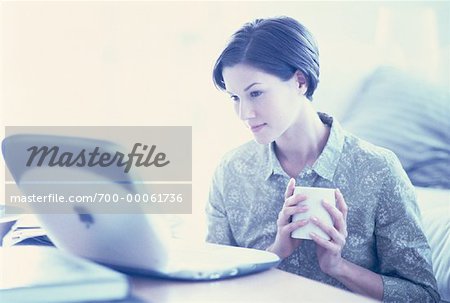 Jeune femme assise à Table avec Mug et ordinateur portable