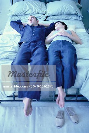 Couple reposant sur le lit avec les jambes pendre au-dessus de bord