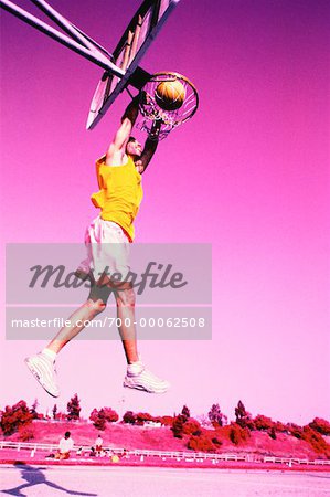 Man Jumping to Slam Dunk Basketball