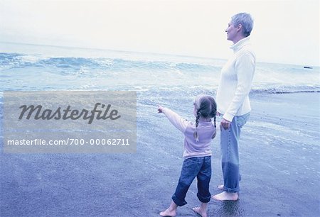 Grandmother and Granddaughter Standing in Surf on Beach