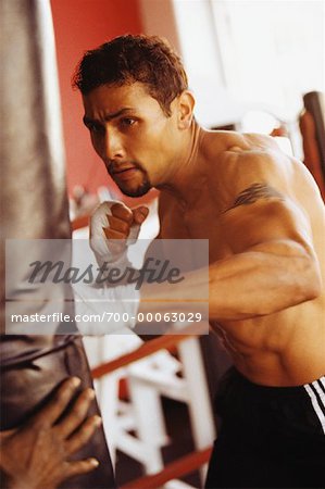 Man Hitting Punching Bag in Gymnasium