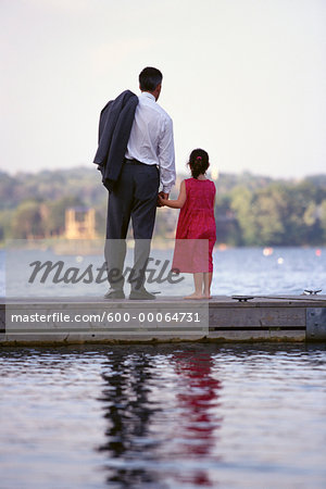 Back View of Father and Daughter Standing on Dock, Holding Hands