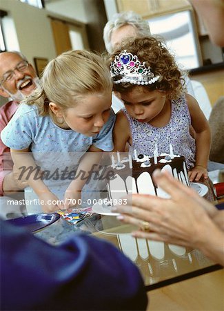 Two Girls Blowing Out Birthday Candles