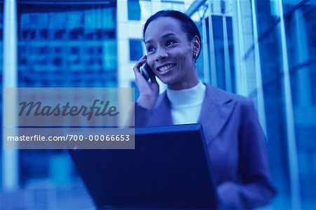 Businesswoman Sitting Outdoors Using Cell Phone and Laptop