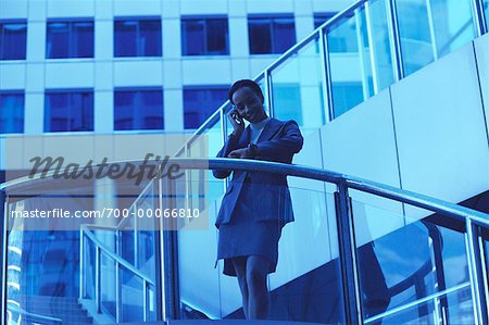 Femme d'affaires en utilisant le téléphone cellulaire regardant montre à l'extérieur