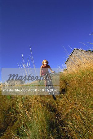 Woman Biking through Field of Tall Grass, Maine, USA