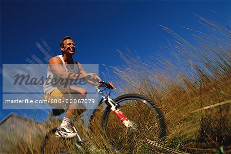 Homme, faire du vélo à travers champ de hautes herbes, Maine, États-Unis