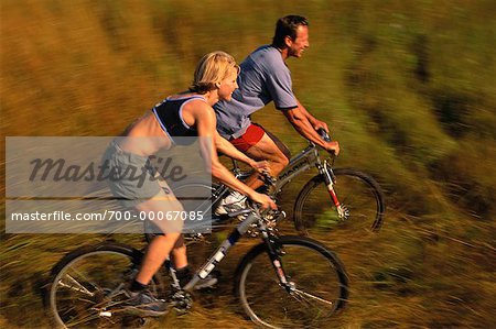 Couple, faire du vélo à travers champ de hautes herbes, Maine, États-Unis