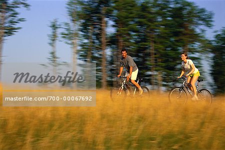 Couple, faire du vélo à travers champ de hautes herbes, lacs de Belgrade, Maine USA