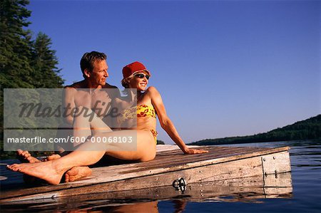 Couple en maillot de bain, reposant sur le quai, lacs de Belgrade, Maine, États-Unis