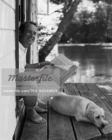 Homme assis dans l'embrasure de la porte, lire le journal avec chien Bala, Ontario, Canada