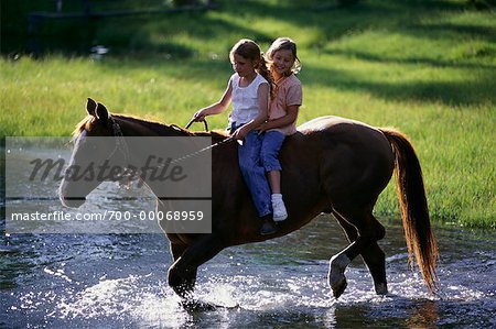 Deux filles d'équitation à cheval à travers les flux