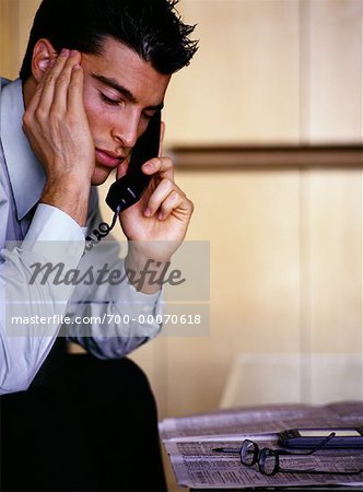 Homme d'affaires en utilisant le téléphone, tête de repos sur la main