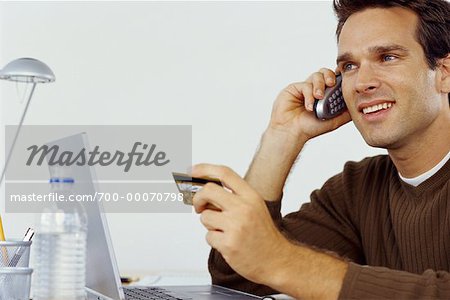 Mann sitzt am Laptopcomputer mit Kreditkarte und Telefon