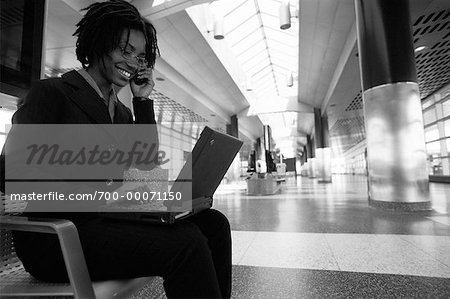 Businesswoman Using Laptop and Cell Phone in Terminal