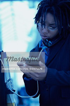 Businesswoman Using Payphone and Electronic Organizer in Terminal