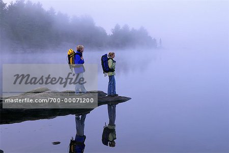 Couple Standing on Rocks in Lake With Fog, Haliburton, Ontario Canada