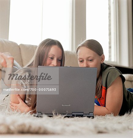 Deux adolescentes gisant sur le plancher à l'aide d'ordinateur portable