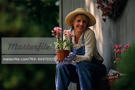 Porträt Frau sitzen am Haus, halten Blumen im Topf