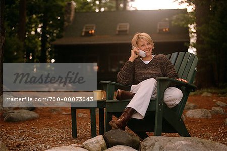 Porträt der Frau im Adirondack Stuhl sitzen, Telefon im freien verwenden